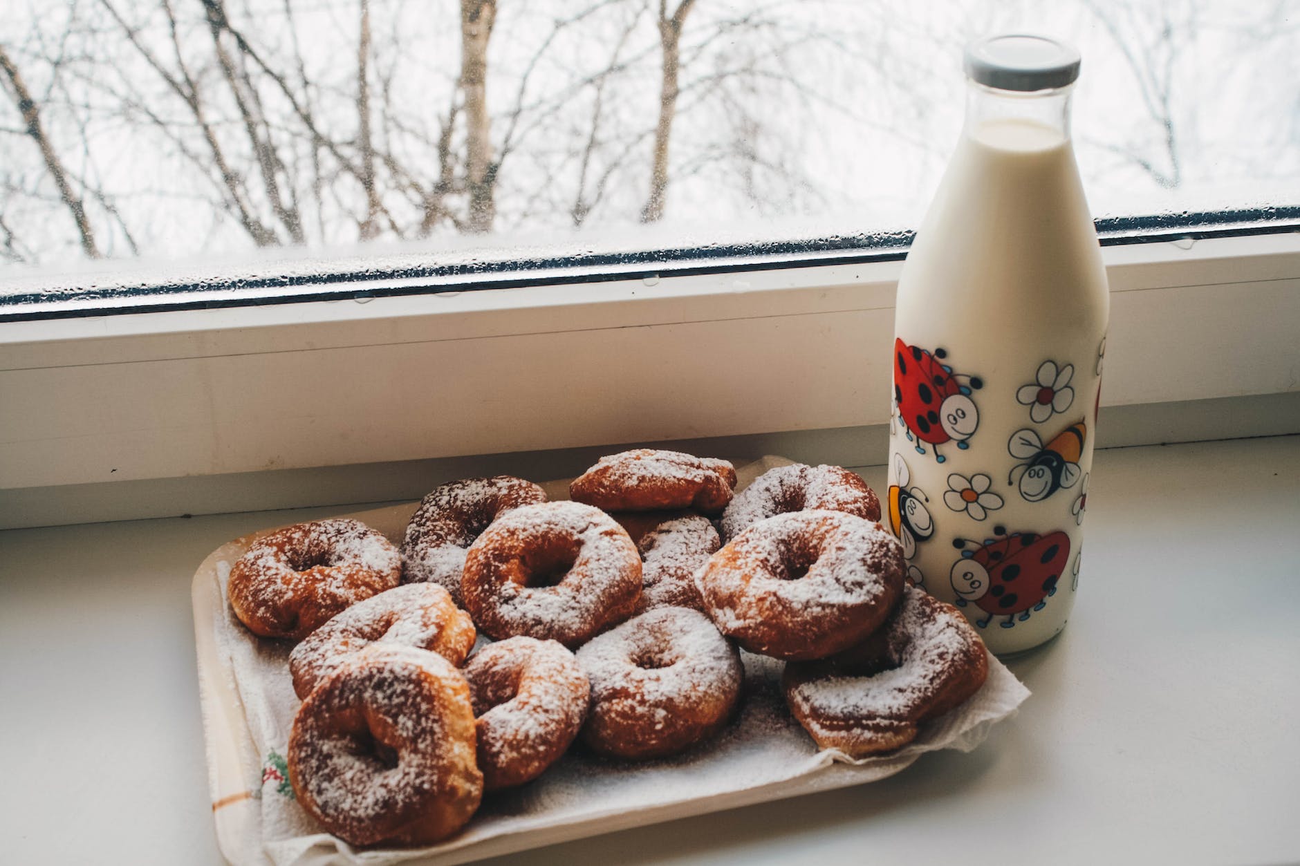 doughnuts and milk bottle near clear glass window